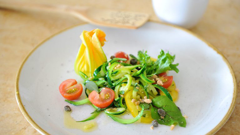 Zucchini-Spaghetti mit Tomate, Mandeln und Kapern.