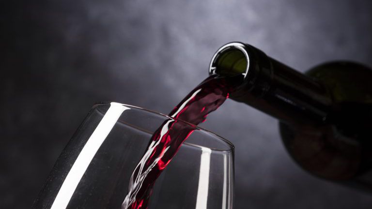 Rotwein wird in ein Glas eingeschenkt