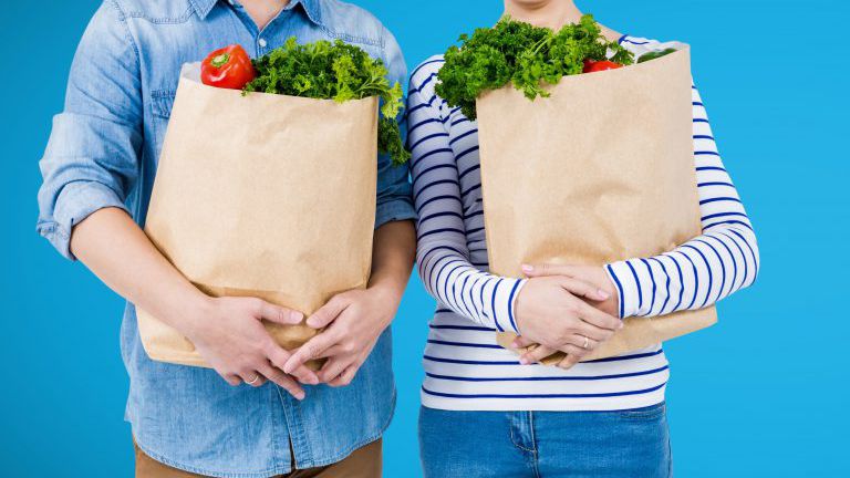 Shoppers mid sections with grocery bags against blue background