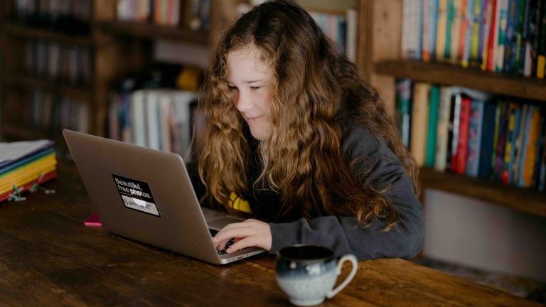 Junges Mädchen sitzt vor dem Laptop