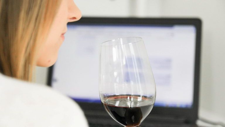 Frau mit Glas Wein vor dem Computer
