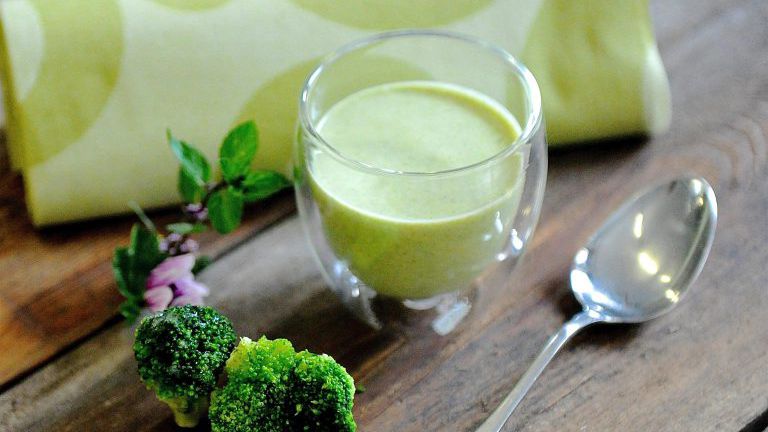 Grüne Suppe im Glas mit Brokkoli und Löffel
