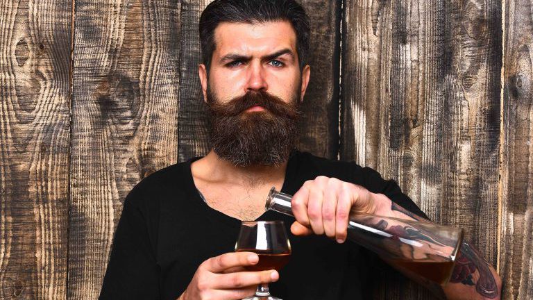 Kerl mit Glas und Flasche Cognac. Service und Verkostung