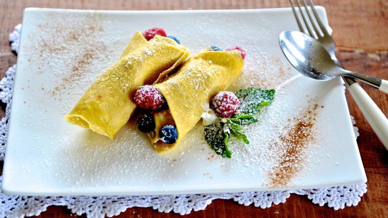 Palatschinken gefüllt mit Beeren, Teller auf einem gehäkelten Deckchen
