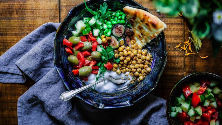 Teller mit mediterranem, vegetarischem Essen, Kichererbsen, Oliven, Brot