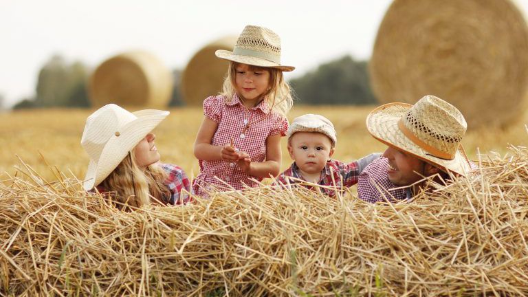 Familie auf Heuhaufen mit Cowboyhüten