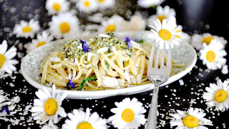 Margaritenblüten und ein Teller mit Pasta