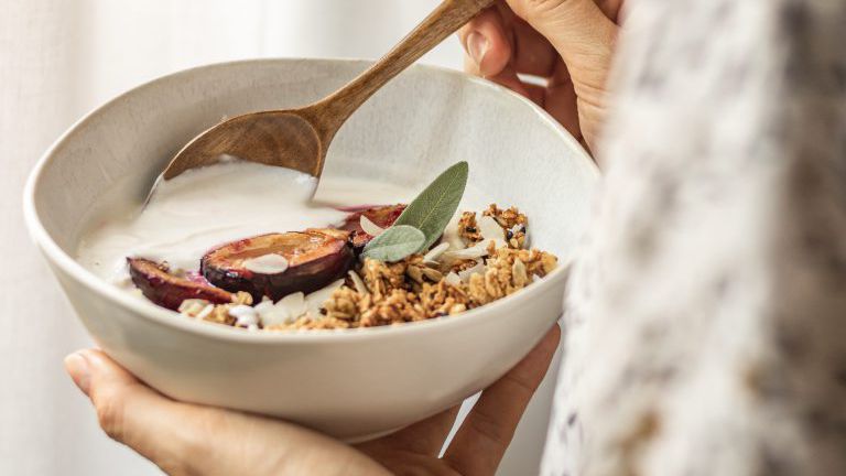 Müslischüssel mit Hand und Holzlöffel