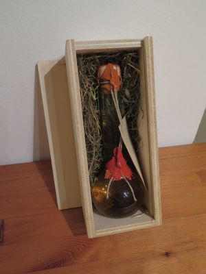 Die Holzschatulle für Geschenkflaschen wird standardmäßig mit Wiesenheu-Unterfütterung ausgeliefert.
